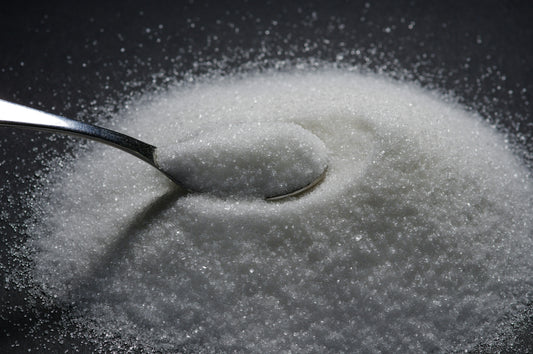 Spoon in a pile of sugar on a black background